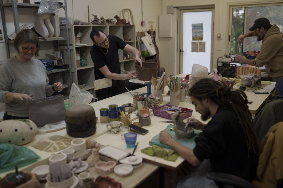 Rotem Katz, 32, background center, head of the security team for Kibbutz Nahal Oz, and his neighbors work on their creations at the pottery workshop in Kibbutz Mishmar HaEmek in northern Israel, Sunday, Feb. 4, 2024. (AP Photo/Leo Correa)