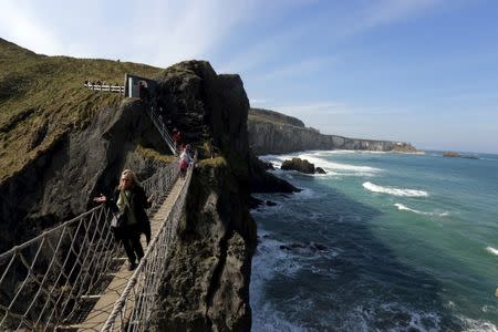 Tourists make their way across Carrick-a-Rede Rope Bridge on the Causeway coast, north of Belfast April 8, 2015. The bridge is suspended 30 metres above sea level and was built 350 years ago by salmon fishermen, according to conservation organisation National Trust. REUTERS/Cathal McNaughton