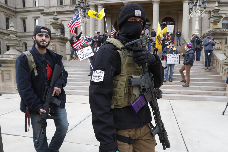 In this April 15, 2020 photo, protesters carry guns outside the Capitol Building in Lansing, Mich. Attorney General Dana Nessel said Friday, May 8, 2020, that a commission overseeing the state Capitol can legally ban guns from the building, contradicting panel leaders' contention that only the Legislature can do so. (AP Photo/Paul Sancya)