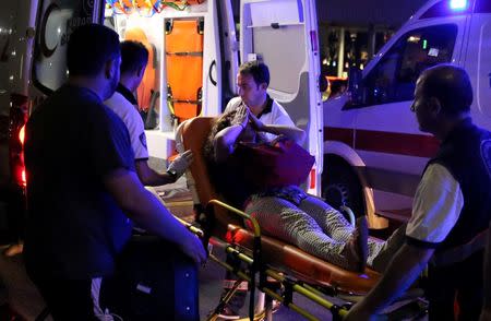 An injured woman covers her face as she is carried by paramedics into ambulance at Istanbul Ataturk airport, Turkey, following a blast June 28, 2016. REUTERS/Goran Tomasevic