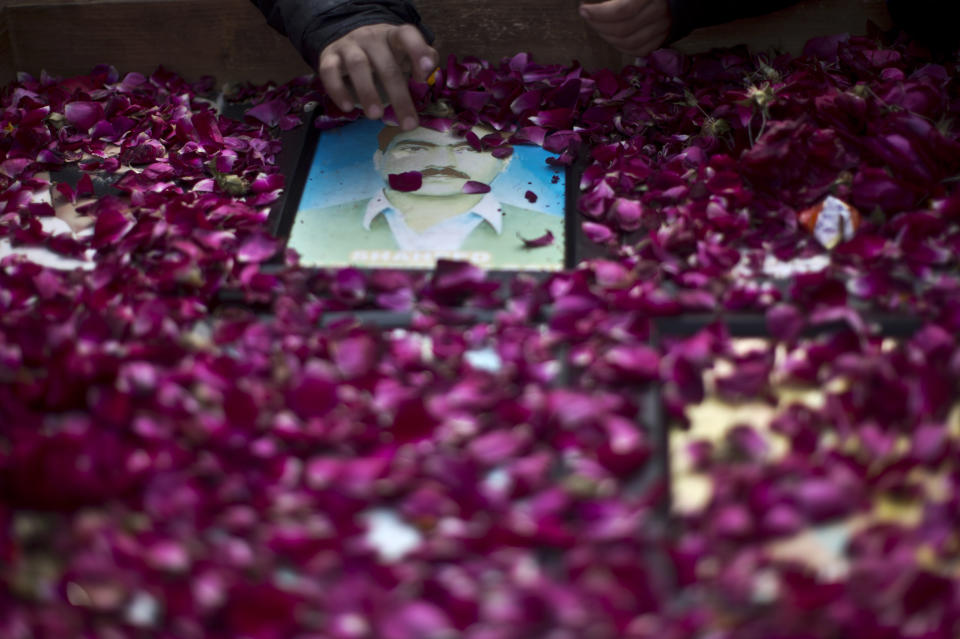 Photographs of missing people are covered with rose petals during a march in Rawalpindi, Pakistan, Friday, Feb. 28, 2014. Affected families walked nearly 3,000 kilometers to reach capital Islamabad and register protest against the abductions and killings of their loved ones by Pakistani security agencies without producing them in court of law. (AP Photo/Muhammed Muheisen)