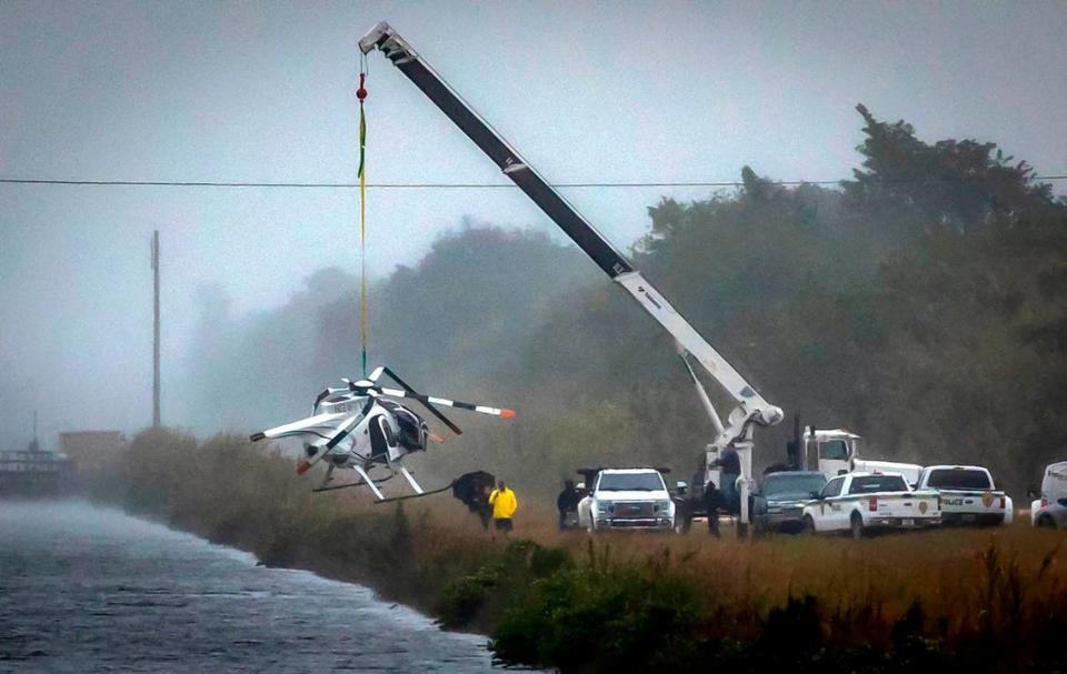 Miami, Florida, December 28, 2023 - A crane hoists out of a canal a helicopter that crashed in Southwest Miami-Dade County on Wednesday, Dec. 27, 2023.