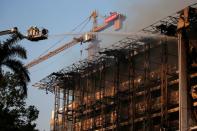 Firefighters stand on a crane as they spray water to extinguish fire at the Attorney's General office in Jakarta