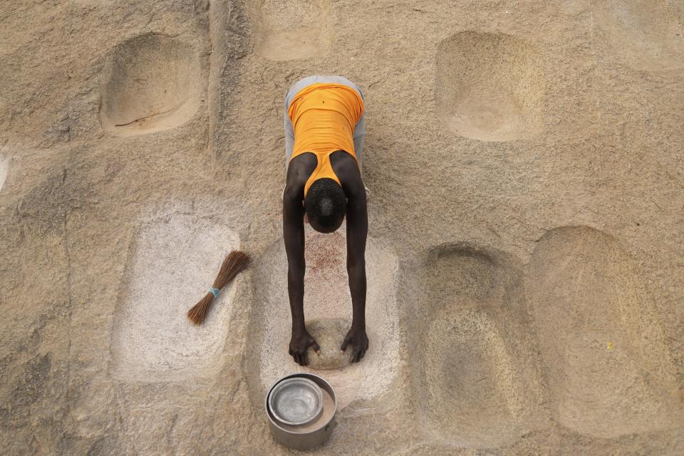 A woman works with flour in Lafon, South Sudan, Tuesday, June 18, 2024. African Parks has set up small hubs in several remote villages and is spreading messages of sustainable practices, such as not killing female or baby animals. (AP Photo/Brian Inganga)