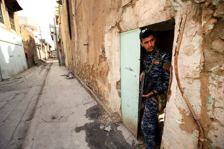 A member of federal police inspects a home burnt by Islamic State militants during a battle with Islamic State militants at Dawasa neighborhood in Mosul, Iraq, March 8, 2017. REUTERS/Thaier Al-Sudani