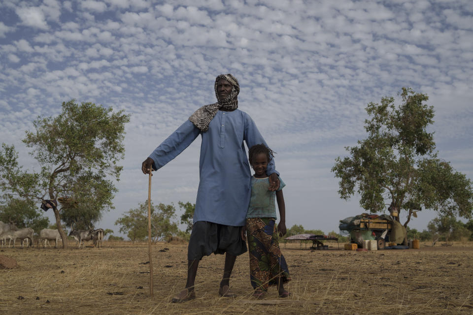 Amadou Altine Ndiaye, 48, stands for a portrait with his daughter, Aminata, 5, where they set up camp in the village of Dendoudy Dow, in the Matam region of Senegal, Thursday, April 20, 2023. (AP Photo/Leo Correa)