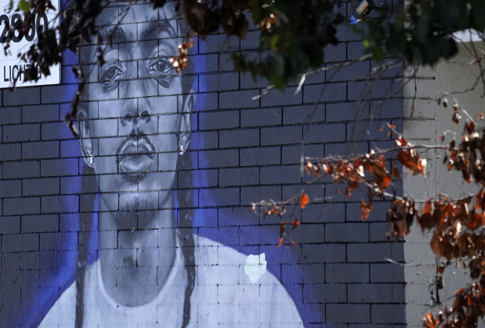A street mural of the late rapper Nipsey Hussle is framed through tree branches, Tuesday, June 28, 2022, in Los Angeles. The many murals of Hussle around Los Angeles speak to the late rapper's lasting legacy. (AP Photo/Chris Pizzello)