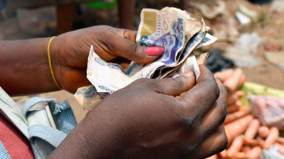 A market vendor with painted nails counts naira in southeastern Nigeria - 2023