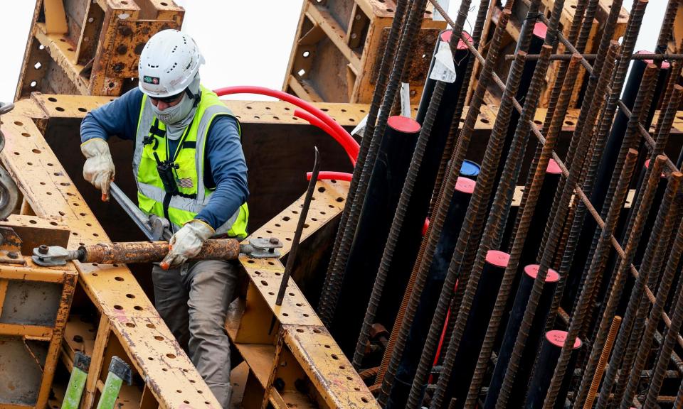 <span>A construction worker helps build the ‘Signature Bridge’ in Miami, Florida. </span><span>Photograph: Joe Raedle/Getty Images</span>