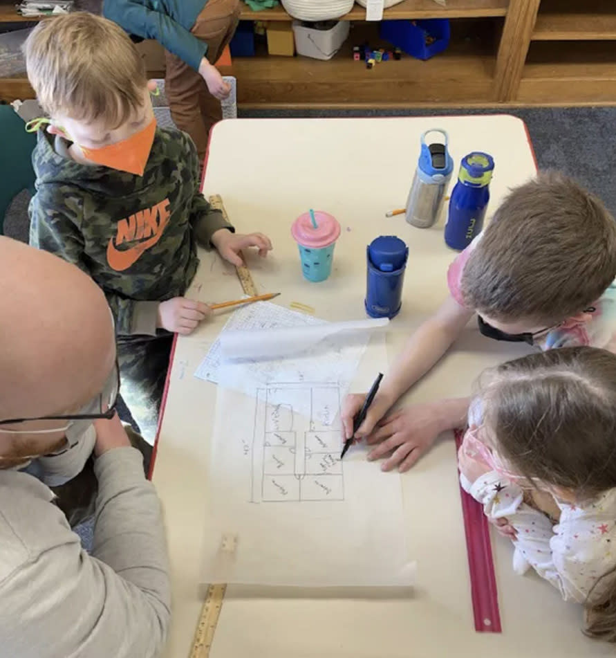 Several children gathered around a drawing table.