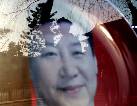 FILE PHOTO: A paramilitary officer is reflected in a souvenir plate bearing the image of China's President Xi Jinping at a shop nearby the Great Hall of the People where the National People's Congress will be held, in Beijing, China March 4, 2015. REUTERS/Kim Kyung-Hoon/File Photo