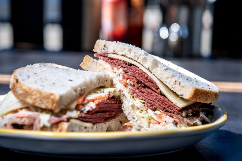 Two halves of a pastrami sandwich stacked on a plate