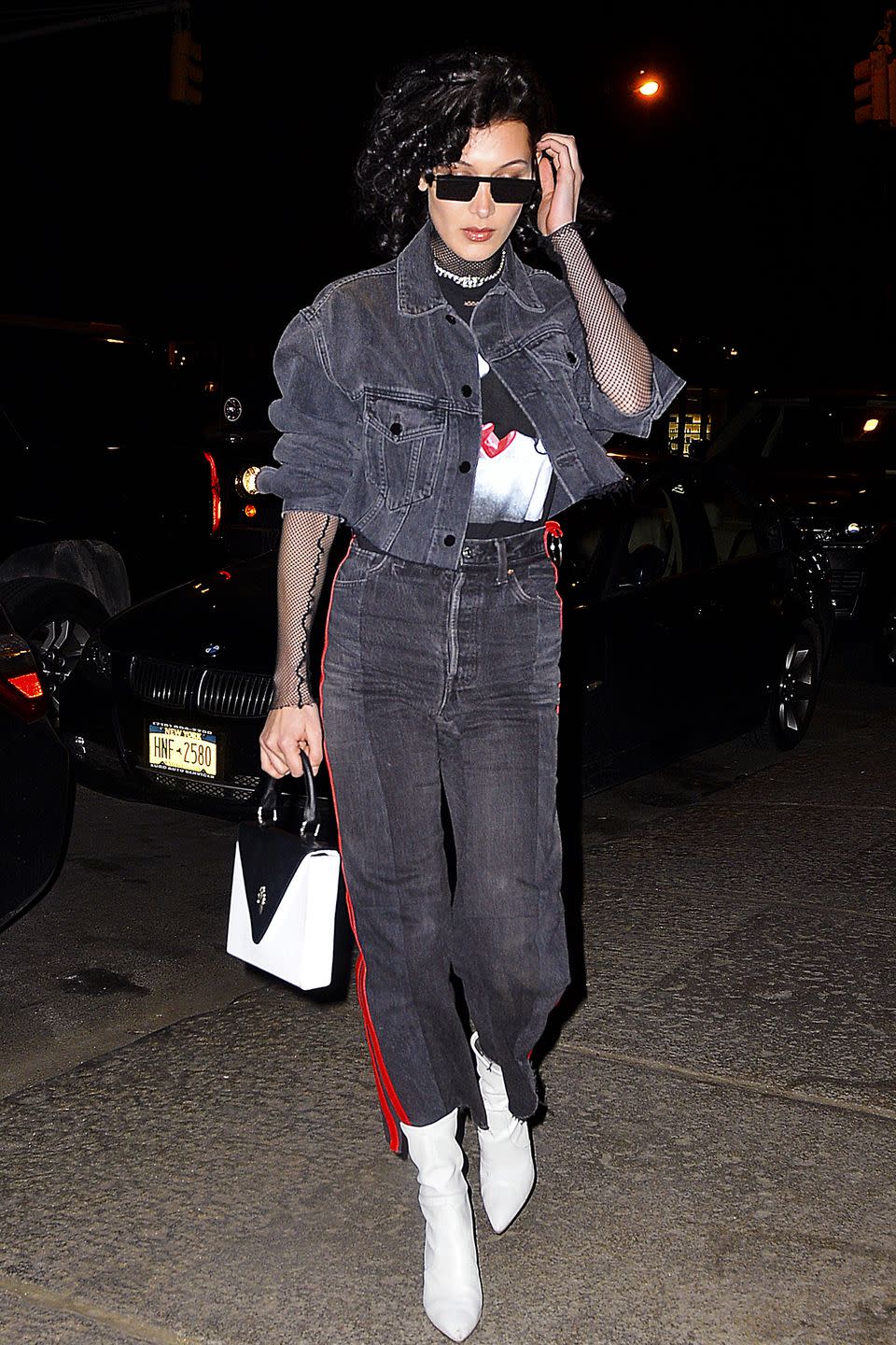 <p>In a sheer fishnet top under a graphic tee and grey Alexander Wang denim jacket with red leather-lined Vetements jeans, Stuart Weitzman boots, a Chrome Hearts bag and black sunglasses while out in New York City. </p>