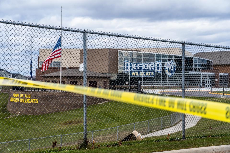 Flags wave at the rear entrance of Oxford High School on Dec. 2, 2021, after an active shooter situation at Oxford High School that left four students dead and seven others with injuries.