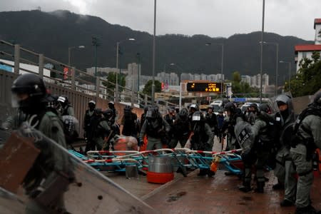 Riot police officers walk over a barricade set up by anti-government protesters in Kowloon district, in Hong Kong