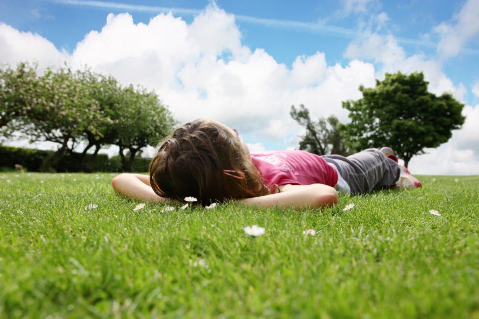 summer activities girl laying on the grass staring up at clouds