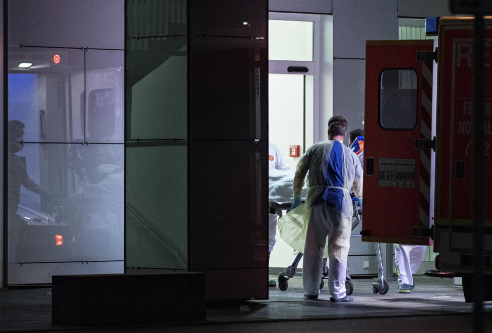 Medical staff in carry the first person infected with the coronavirus in the German state of North Rhine Westphalia out of an ambulance into the Liver and Infection Center of the University Hospital in Duesseldorf, Germany, Wednesday, Feb 26, 2020. (Guido Kirchner/dpa via AP)