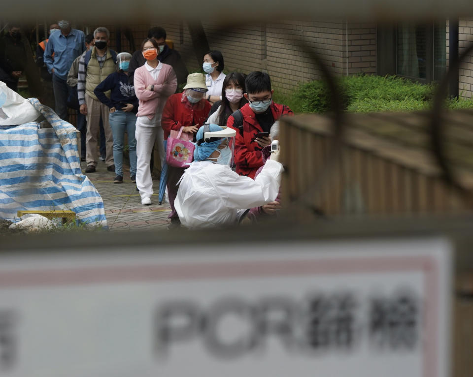 台灣新冠肺炎本土情延燒，不少民眾21日上午前往台北市北投區一家醫院的篩檢站，等候PCR檢驗，圖為醫護人員替排隊民眾量測額溫。
（中央社）