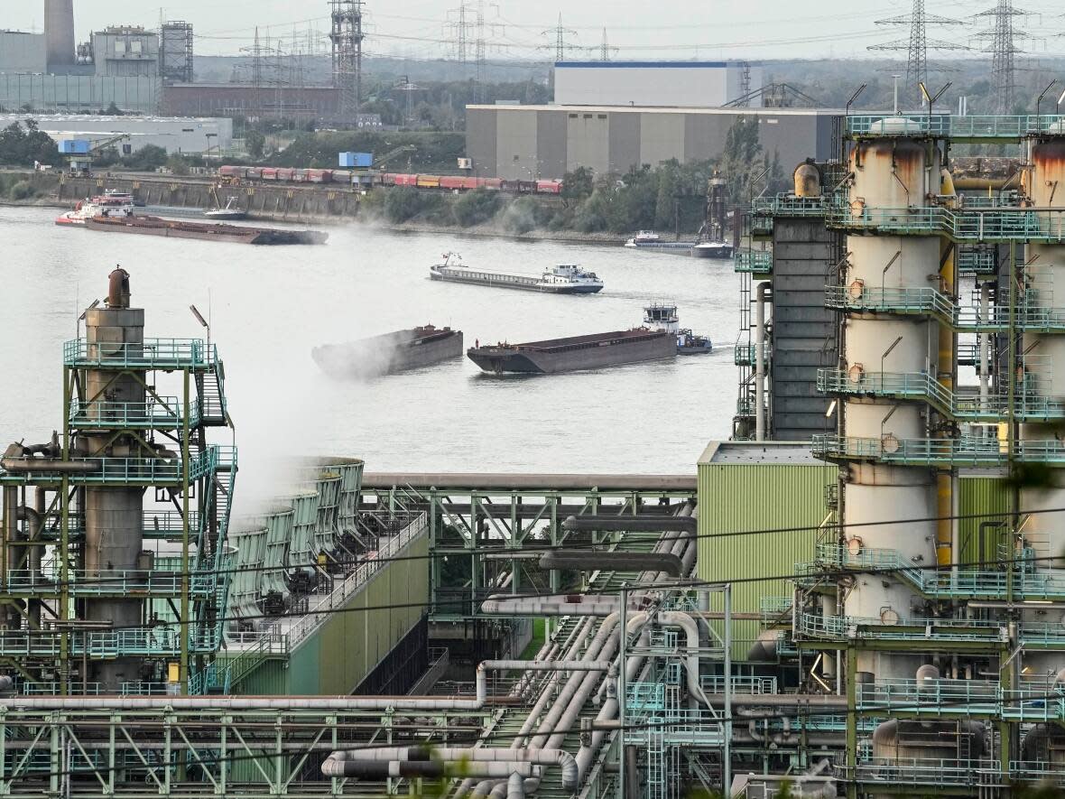 Freight ships are seen on the Rhine River at the Schwelgern coking plant of German steel producer thyssenkrupp Steel Europe in Duisburg, Germany, last year. The European Union proposed drastic cuts in greenhouse gas emissions on Tuesday, which would require major changes across all sectors by 2040. (Martin Meissner/Associated Press - image credit)