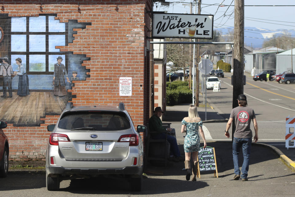 Customers walk toward the Last Waterin' Hole restaurant in North Plains, Ore., on March 17, 2023. Just over the horizon, in the city of Hillsboro, Ore., is a large facility owned by Intel, the semiconductor chip maker. More semiconductor facilities might be cropping up closer to North Plains if a bill in the Legislature becomes law, giving the governor the authority to expand urban growth boundaries to create large tracts for chip manufacturers to build. (AP Photo/Andrew Selsky)