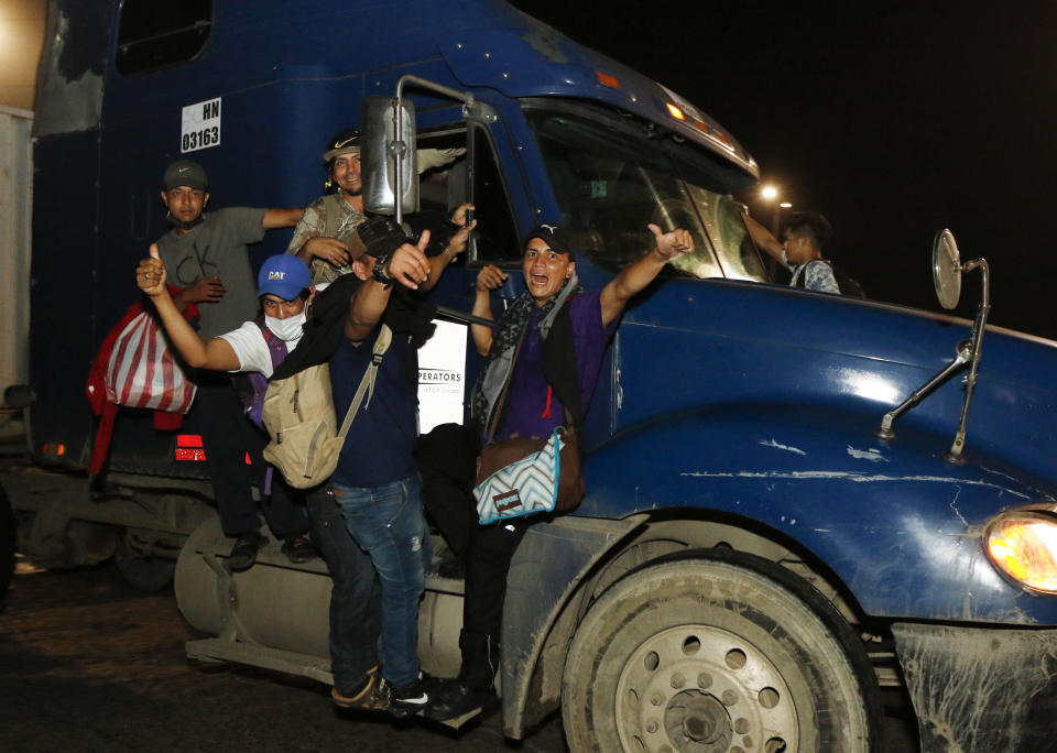 Migrants give a thumbs up from the side of a moving truck as they depart San Pedro Sula, Honduras, before dawn Friday, Jan. 15, 2021 in hopes of reaching the U.S. border. The group quickly dispersed along the heavily-trafficked highway to the border town of Agua Caliente, but estimates of their number ranged from 2,000 to more than twice that. (AP Photo/Delmer Martinez)