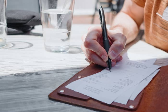 a hand filling out a restaurant bill