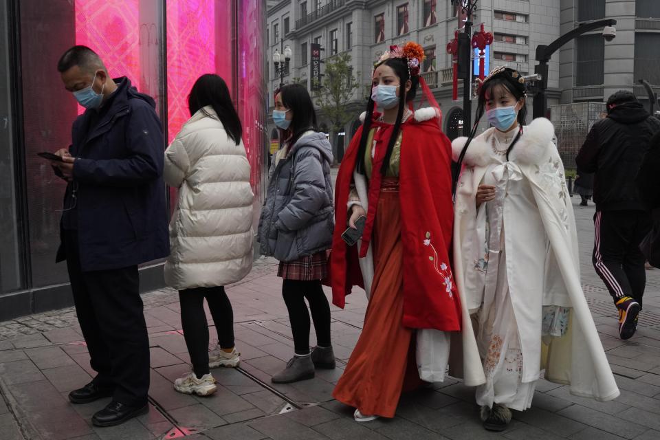 Chinese women dressed in traditional costumes and wearing masks visit a popular shopping street in Wuhan in central China's Hubei province, Saturday, Jan. 23, 2021. A year after it was locked down to contain the spread of coronavirus, the central Chinese city of Wuhan has largely returned to normal, even as China continues to battle outbreaks elsewhere in the country. (AP Photo/Ng Han Guan)