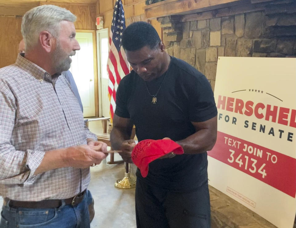 Republican U.S. Senate nominee Herschel Walker signs a campaign hat for former Georgia state lawmaker Terry Rogers on Thursday, July 21, 2022, in Alto, Georgia. Walker, a former University of Georgia and NFL football star, is trying to unseat Democratic Sen. Raphael Warnock in what is expected to be a tight race that will help determine which party controls the Senate in the second half of President Joe Biden’s term. (AP Photo/Bill Barrow)