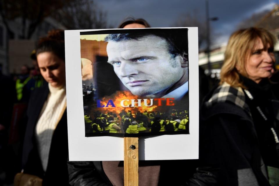 A woman holds a placard picturing French President Emmanuel Macron and reading 