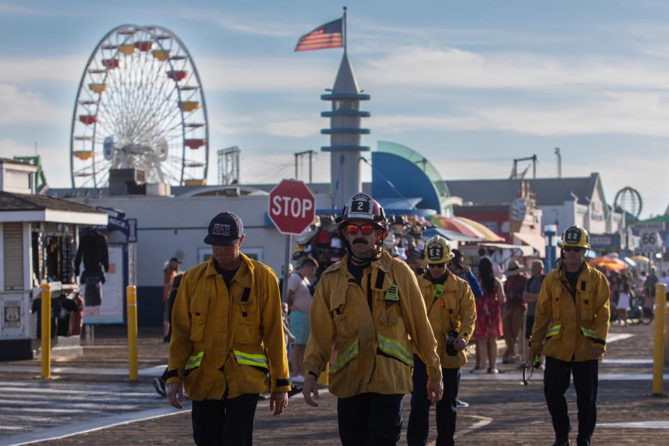 Firefighters walk at Santa Monica Pier after a man, who claimed to have a bomb, climbed the ferris wheel and refused to come down, in Santa Monica, California, on October 09, 2023.