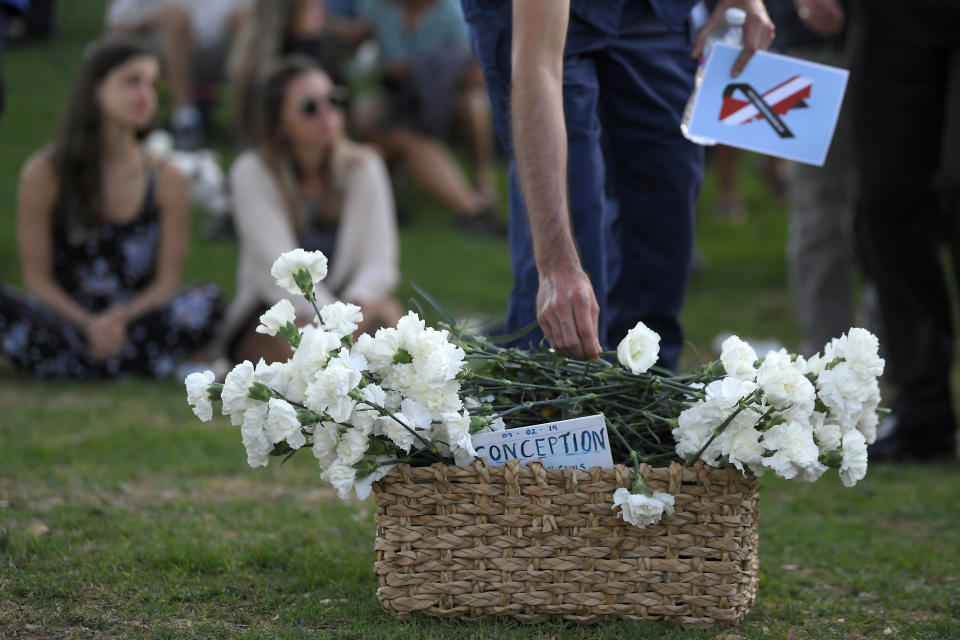 An attendee places a flower in a basket during a vigil Friday, Sept. 6, 2019, in Santa Barbara, Calif., for the victims who died aboard the dive boat Conception. The Sept. 2 fire took the lives of 34 people on the ship off Santa Cruz Island off the Southern California coast near Santa Barbara. (AP Photo/Mark J. Terrill)