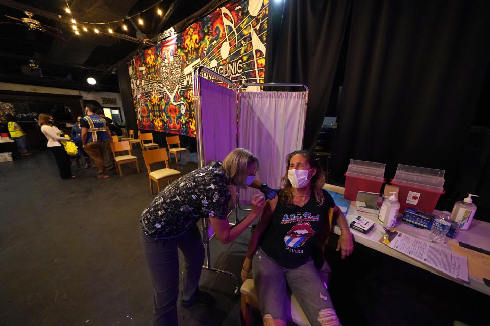 Allison Richter receives the Moderna COVID-19 vaccine from volunteer RN Maggie Baker, during a vaccine event hosted by Nola Ready, where people received a free drink at the bar if they received a COVID-19 vaccine, at The Howling Wolf, a music venue and bar, in New Orleans, Tuesday, April 13, 2021. Louisiana is making a full-court press to get shots in arms, with sometimes creative outreach to make it as easy as possible to get vaccinated. (AP Photo/Gerald Herbert)