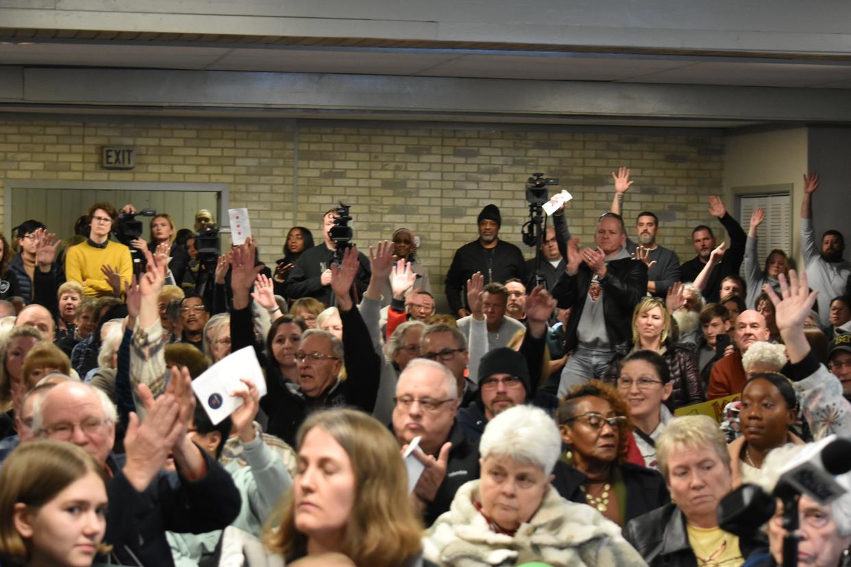 Dozens of people raise their hand to signal their opposition to the proposed site for a new low-barrier homeless shelter on South Bend's northwest side during a public meeting on Thursday, Feb. 1, 2024.
