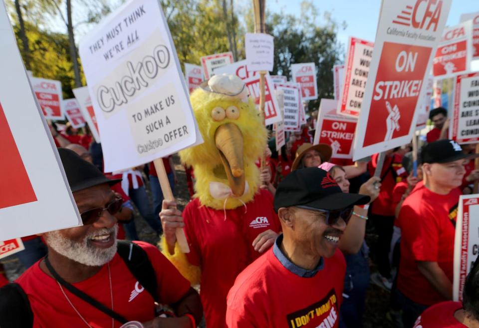 Strikers wearing red hold picket signs.