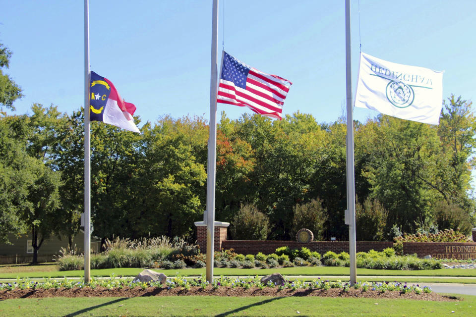 The North Carolina flag, American flag and Hedingham flag all fly at half-staff at the entrance to the Hedingham Golf Club in Raleigh, N.C., on Friday, Oct. 14, 2022, after a shooting in the community left five dead Thursday night, including one off-duty police officer. (AP Photo/Hannah Schoenbaum)