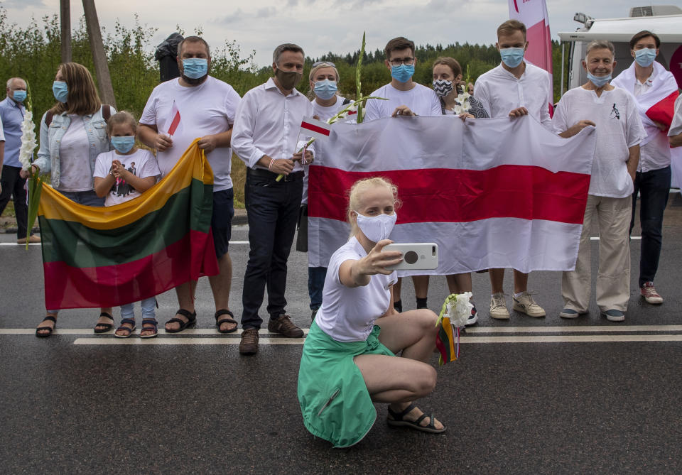 A supporter of Belarus opposition from Lithuania takes a selfie in front of the historical Belarusian flag during the "Freedom Way", a human chain of about 50,000 strong from Vilnius to the Belarusian border, during a protest near Medininkai, Lithuanian-Belarusian border crossing east of Vilnius, Lithuania, Sunday, Aug. 23, 2020. In Aug. 23, 1989, around 2 million Lithuanians, Latvians, and Estonians joined forces in a living 600 km (375 mile) long human chain Baltic Way, thus demonstrating their desire to be free. Now, Lithuania is expressing solidarity with the people of Belarus, who are fighting for freedom today. (AP Photo/Mindaugas Kulbis)