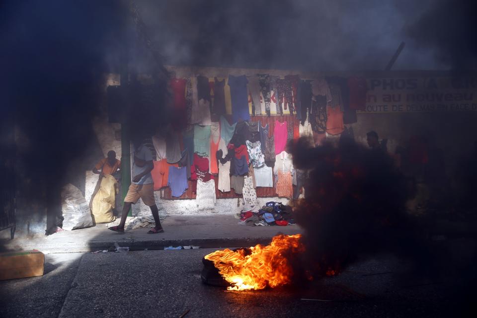 Smoke from tires set fire by protesters fills a street in Delmas where vendors sell clothing during a countrywide strike demanding the resignation of Haitian President Jovenel Moise in Port-au-Prince, Haiti, Monday, Feb. 1, 2021. Opposition leaders are pushing for Moïse to step down on Feb. 7 while Moïse has said his term ends in February 2022. (AP Photo/Dieu Nalio Chery)