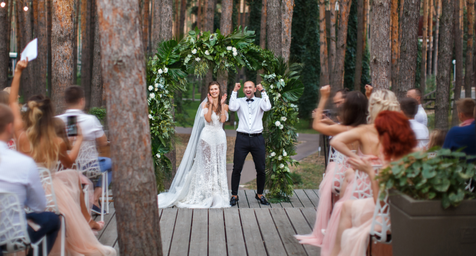 A bride and groom cheer in front of their guests after being married.