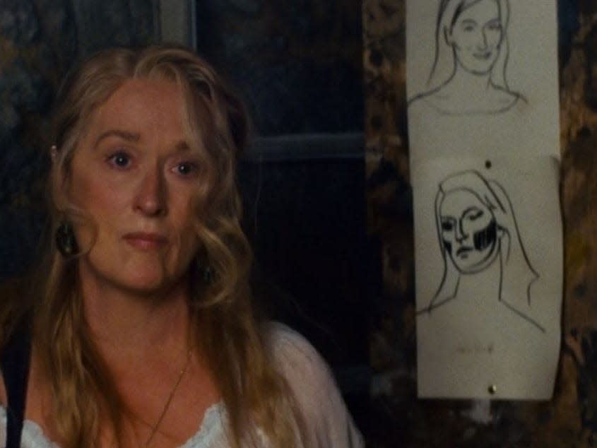 donna standing next to sketches of her face in a scene in mamma mia