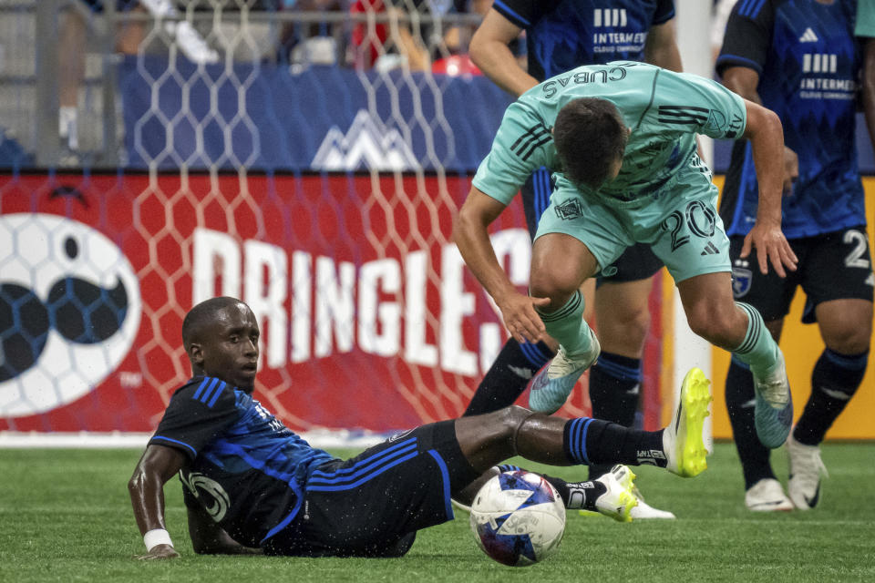 San Jose Earthquakes' Jamiro Monteiro, left, slide-tackles Vancouver Whitecaps' Andrés Cubas (20) during first-half MLS soccer match action in Vancouver, British Columbia, Sunday, Aug. 20, 2023. (Ethan Cairns/The Canadian Press via AP)