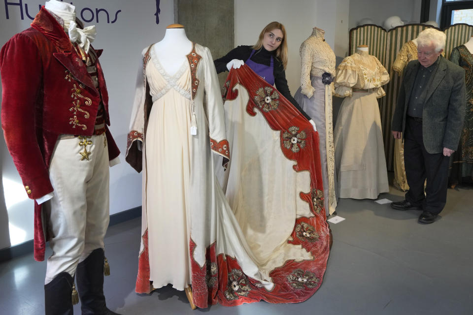 A costume handler arranges Kate Winslet's costume as Sylvia Llewelyn Davies in the film Finding Neverland, 2004 as John Bright, right, looks on, as it is displayed at Kerry Taylor Auctions in London, Tuesday, Feb. 27, 2024. The costume estimated at 1,500-2,500 UK Pounds (1,900-3,200 US Dollars) is one of 69 that will be for auction in the Lights Camera Auction event on March 5. The costumes have been donated by Cosprop in support of The Bright Foundation, an arts education charity, established and funded by John Bright, to provide life-enhancing, creative experiences for children and young people facing disadvantage. (AP Photo/Kirsty Wigglesworth)