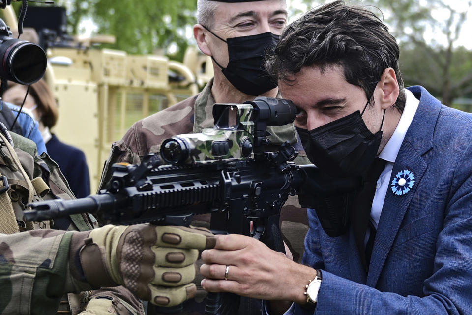 FILE - Then French Secretary of State and Government's spokesperson Gabriel Attal holds a machine gun during a visit to the military camp of Satory in Versailles-Satory, west of Paris, Friday May 7, 2021. French President Emmanuel Macron's choice to appoints a 34-year-old prime minister surprised many _ because of his young age and relatively short career. But Gabriel Attal has become in recent years one of the most prominent and ambitious figures on the French political scene, considering there's "nothing greatest than serving France." (Martin Bureau, Pool via AP, File)