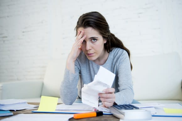 Young woman holding her head while going through paperwork.