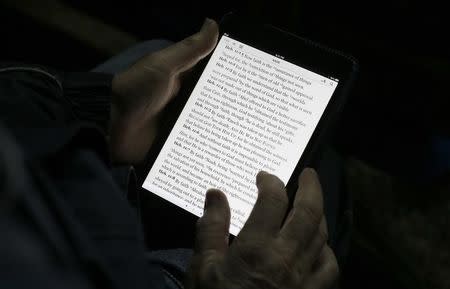 A man reads the bible from an iPad mini at the "Christ is the Answer International Ministries" group's camp near Florence February 2, 2013. REUTERS/Max Rossi