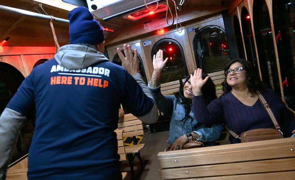 An ambassador with the City of Fresno high-fives passengers after asking their opinion of the new FresnoHOP trolley service Friday night, Nov. 10, 2023 in Fresno. T
