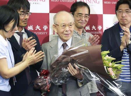 Meijo University professor Isamu Akasaki (C) is presented with a bouquet of flowers from his laboratory staff members during a news conference at Meijo University in Nagoya, central Japan, in this photo taken by Kyodo October 7, 2014. Mandatory credit REUTERS/Kyodo