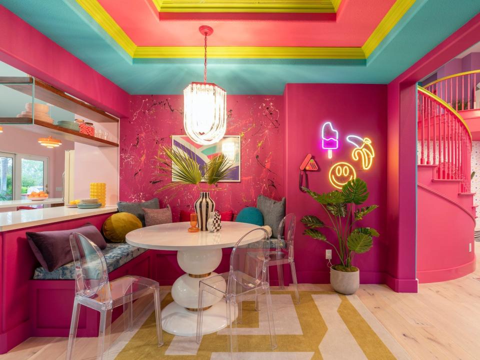 An eating area with pink walls and a white table.