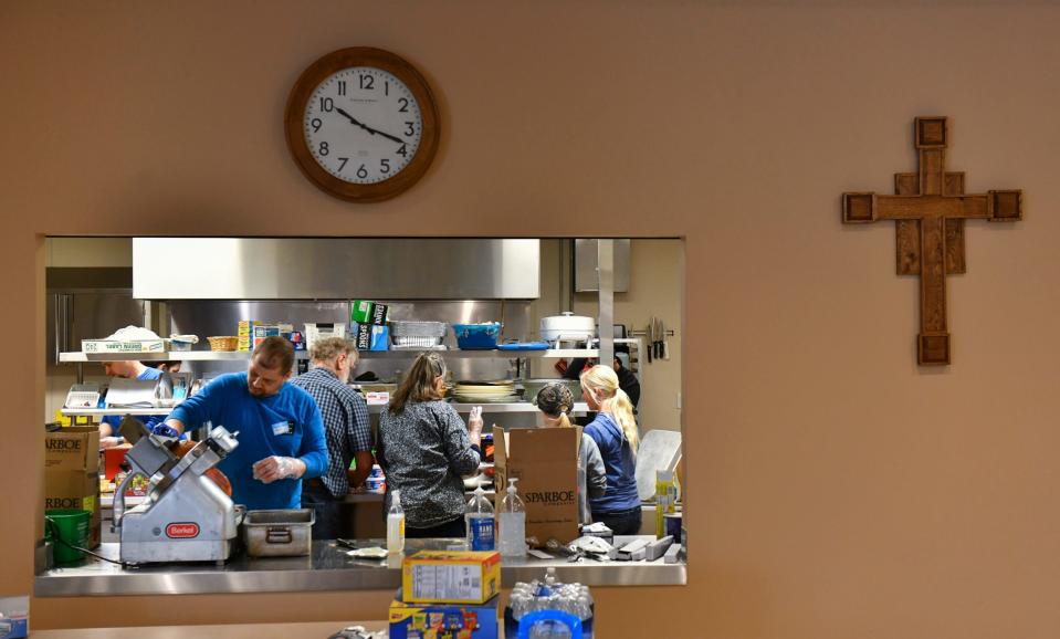 Volunteers work as part of a Faith Feeds MN effort to provide hundreds of Easter meals to local residents Thursday, April 14, 2022, in the kitchen area of Heritage Hall at the Church of St. Joseph. 