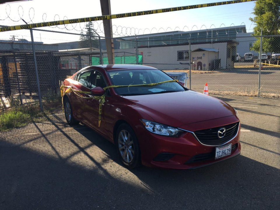 A red Mazda with police tape on it.