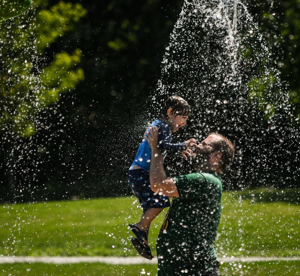 A.J. Miller and son Griffyn, 3, of Lansing beat the Monday afternoon heat at the Hawk Island Park splashpad in Lansing, June 28, 2021.  "I grew up on the westside, and we didn't have parks like this when I was a kid," A.J. says.  "Closest thing we had was the big sledding hill off of Michigan Avenue which is overgrown now, so we really appreciate this place."  The family utilizes the park regularly, including the tubing hill in the winter.